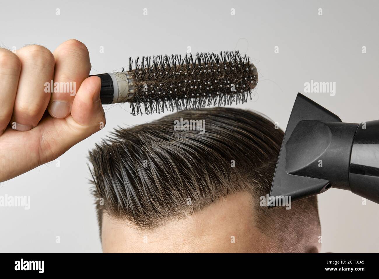 Homme coiffant ses cheveux avec un sèche-cheveux et une brosse ronde. Soins  capillaires à la maison après le salon de coiffure. Mode Mans et coupe de  cheveux moderne Photo Stock - Alamy