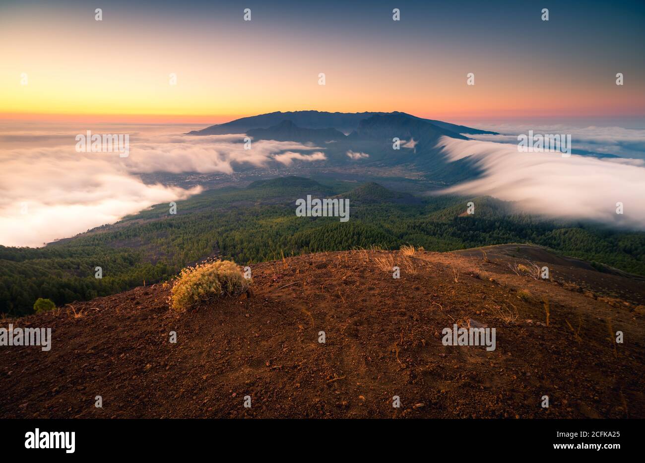Paysage majestueux de la chaîne de montagnes couverte de nuages et de vallée avec des arbres sous un ciel bleu sans nuages Banque D'Images