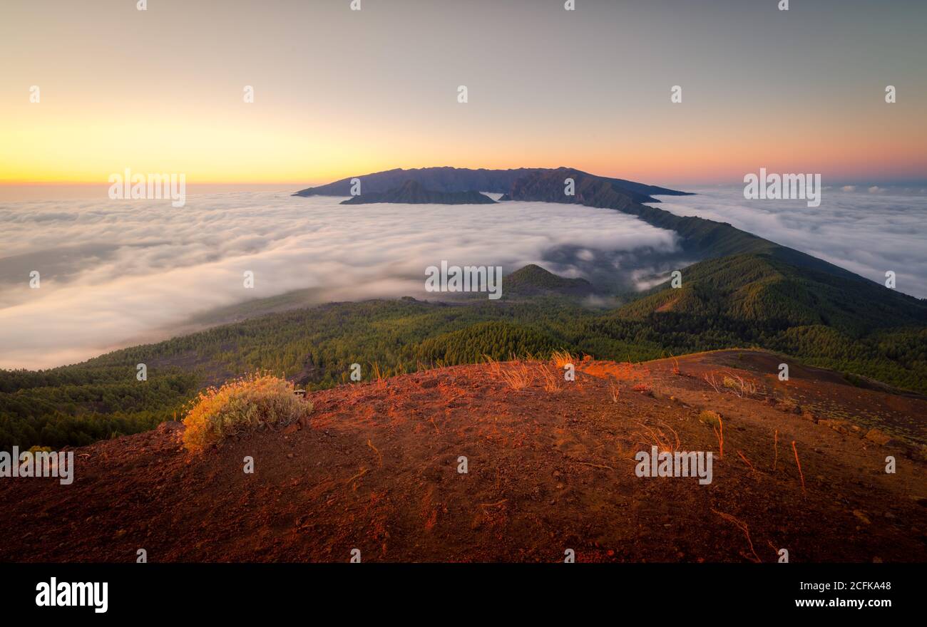 Paysage majestueux de la chaîne de montagnes couverte de nuages et de vallée avec des arbres sous un ciel bleu sans nuages Banque D'Images