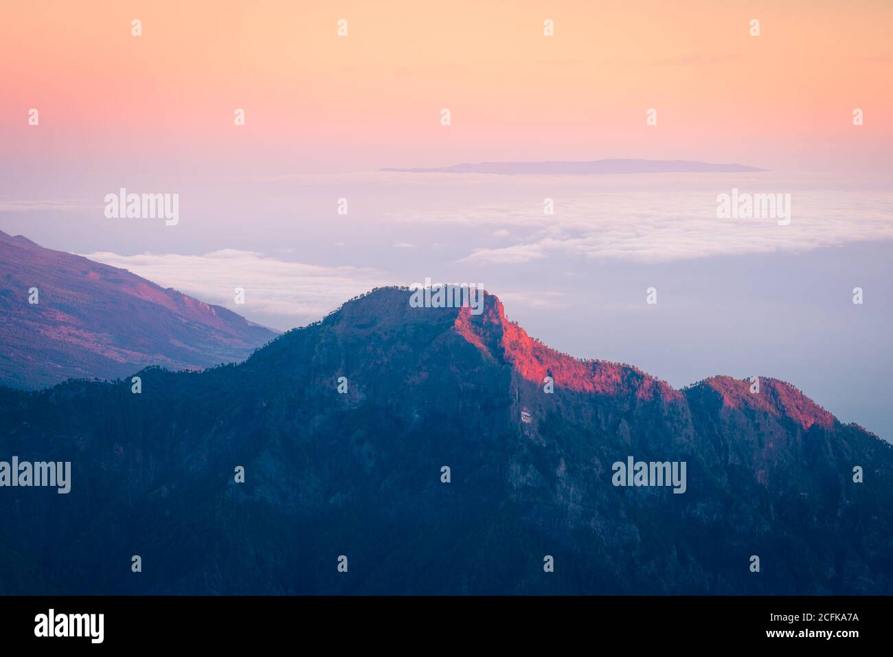 Paysage majestueux de la chaîne de montagnes couverte de nuages et de vallée avec des arbres sous un ciel bleu sans nuages Banque D'Images