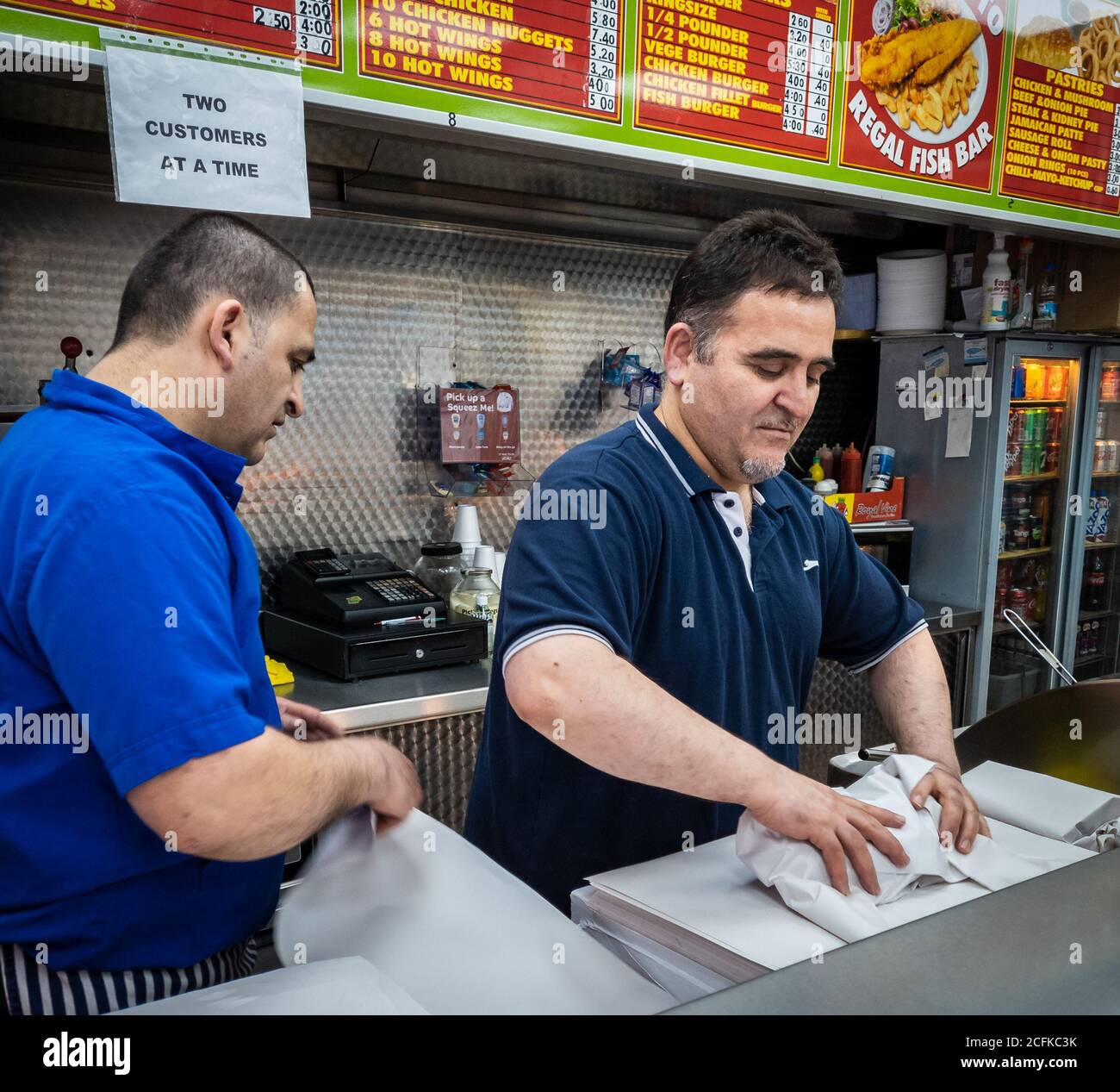 Les travailleurs des magasins de Fish and chips sont occupés à servir les clients Banque D'Images