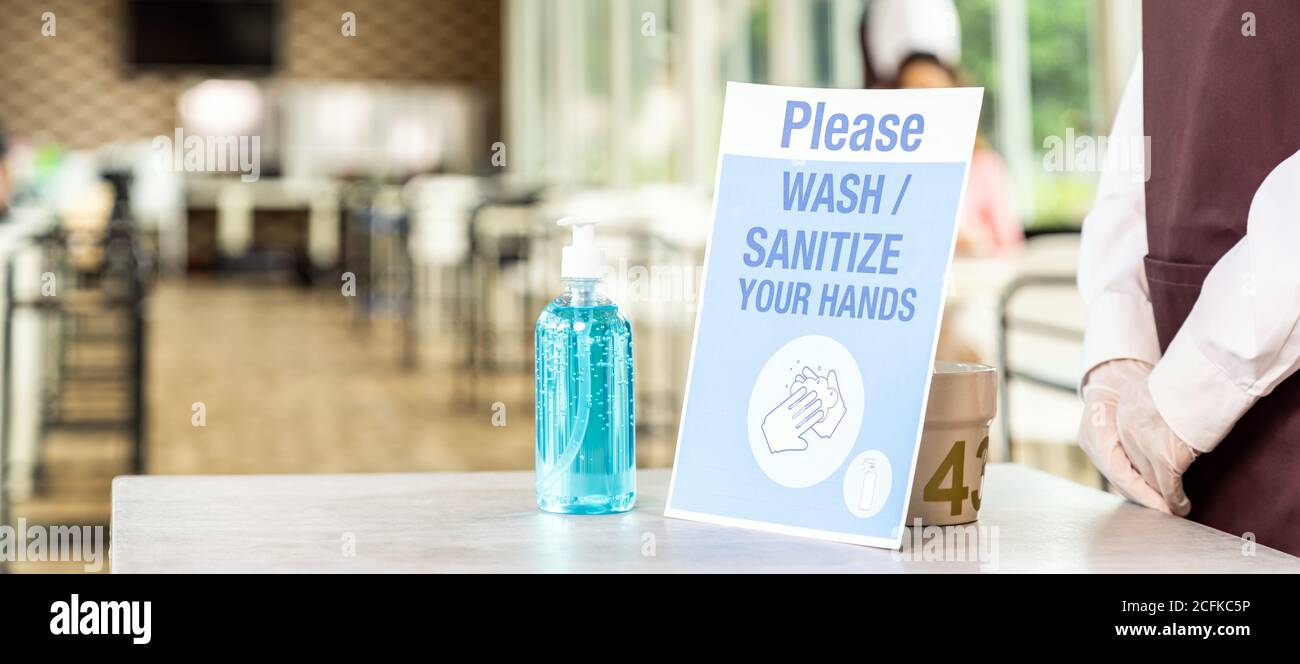 Vue panoramique du stand de serveuse asiatique avec gel alcool ou désinfectant pour les mains avec sa signalisation dans le nouveau restaurant normal. Nouvelle norme et hygiène pour res Banque D'Images