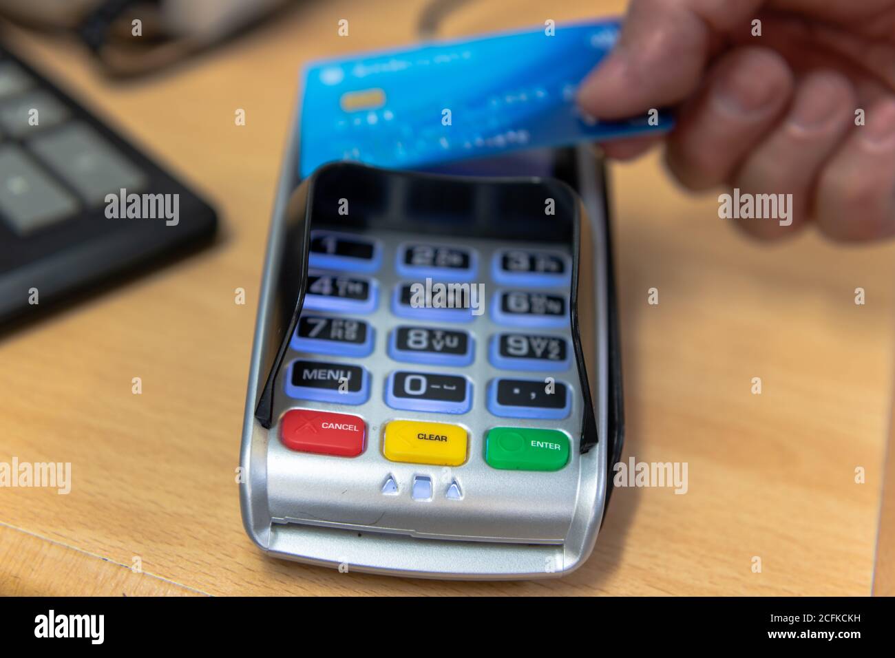 Un client effectuant un paiement par carte sans contact sur un lecteur de carte dans un magasin de détail. Banque D'Images