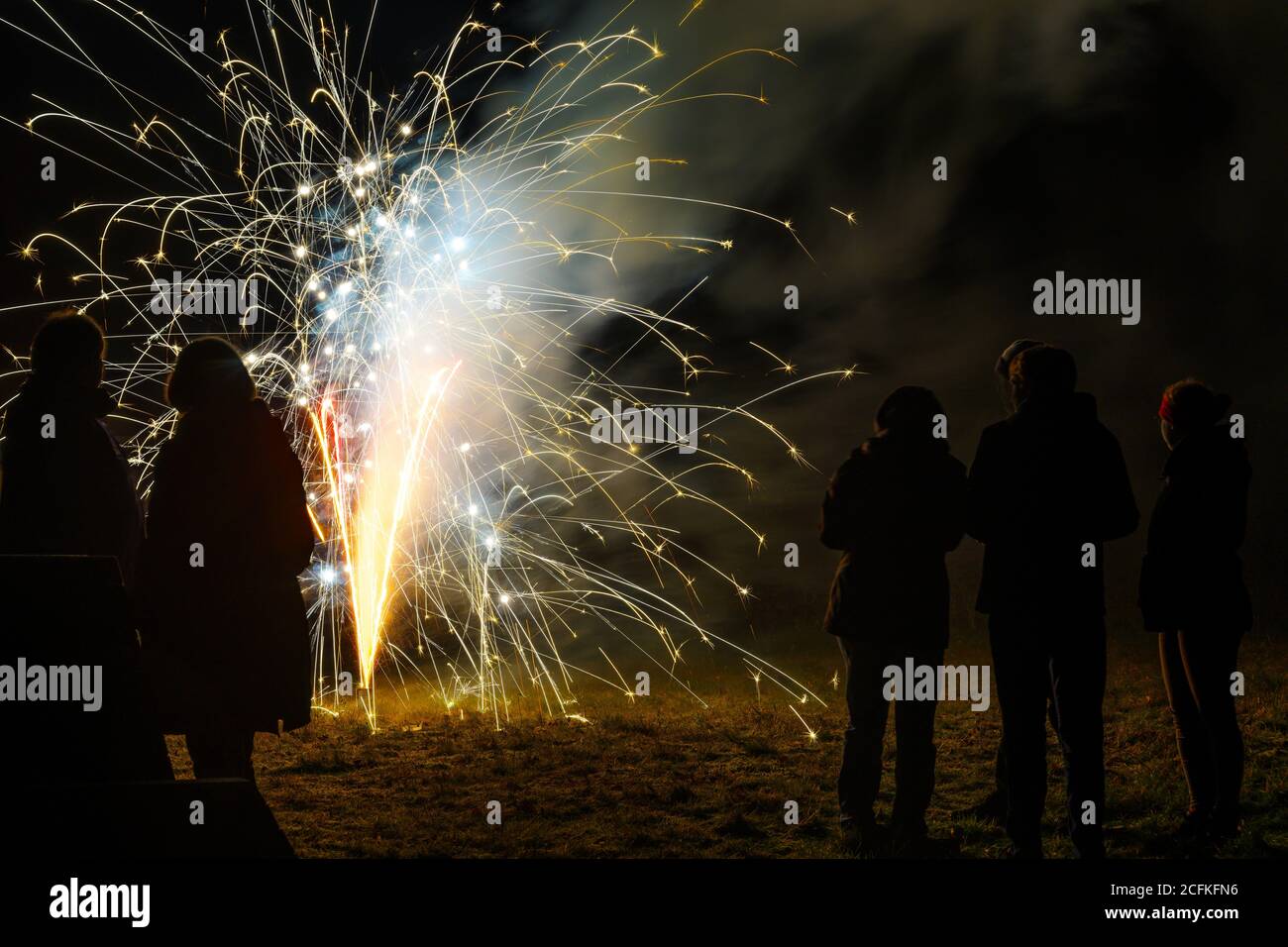 La fontaine de feu d'artifice du nouvel an et les gens comme silhouettes sont debout dans l'obscurité pour célébrer la nouvelle année à minuit, espace de copie Banque D'Images