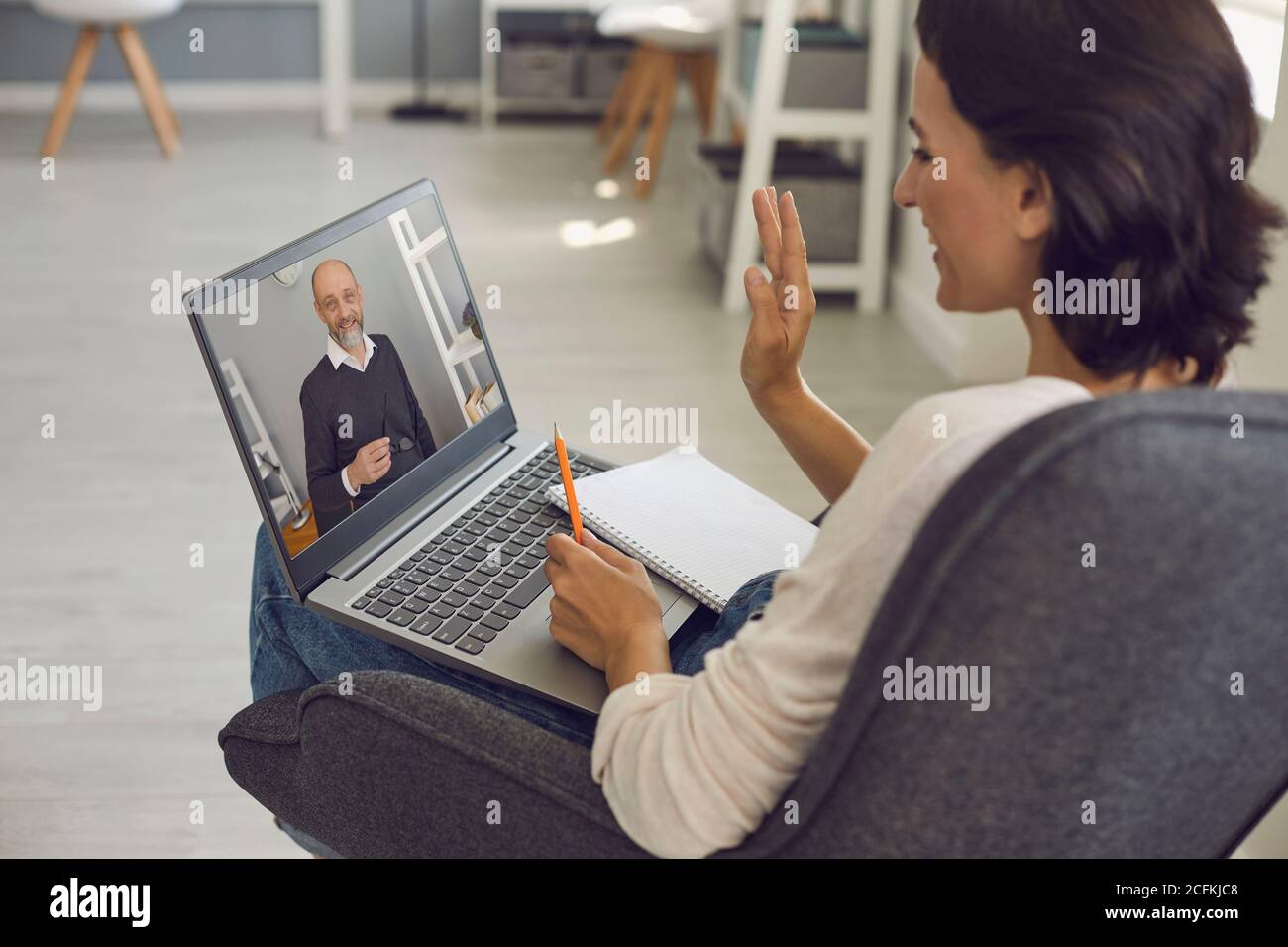Jeune femme à la maison avec un ordinateur portable étudiant en ligne. Apprendre à l'école, l'université en ligne. Homme senior enseignant donnant la conférence sur l'Internet. Concept de Banque D'Images