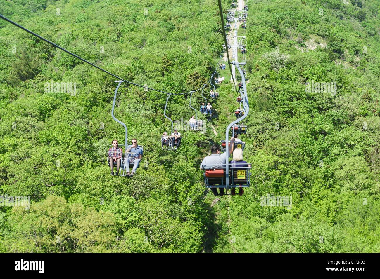Gelendzhik, Russie - avril 30.2017 : les touristes montent et descendent en téléphérique au-dessus du printemps et de la pente de la chaîne de montagnes de Markotkh dans le Safari Banque D'Images