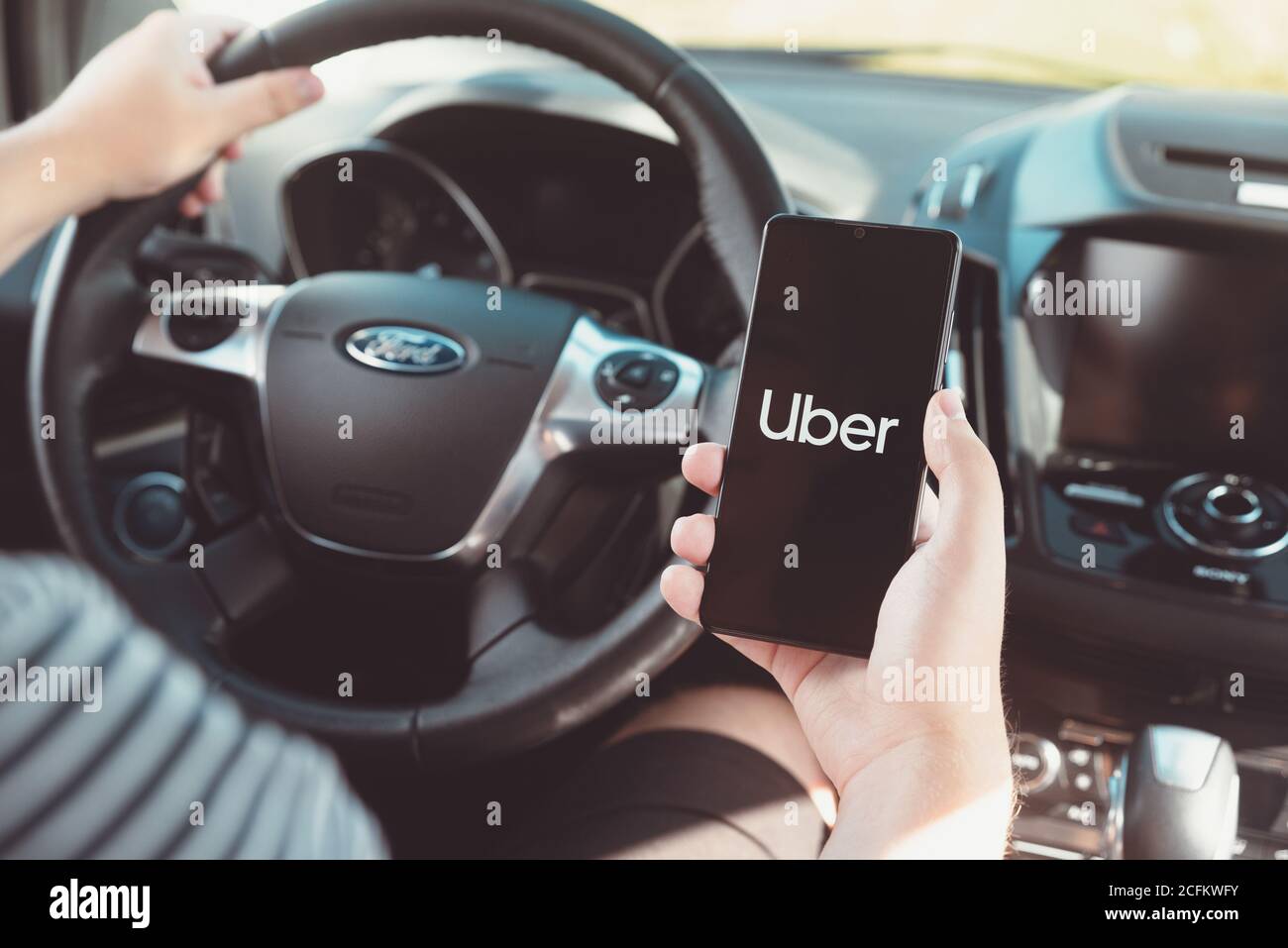 Wroclaw, Pologne - 25 AOÛT 2020 : conducteur Uber tenant un smartphone en voiture. Uber est un service de partage-économie pour le transport ubran. Banque D'Images