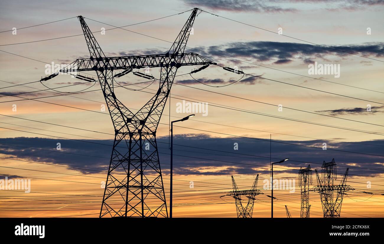 Les tours de transmission de puissance silhouettes au coucher du soleil. Banque D'Images