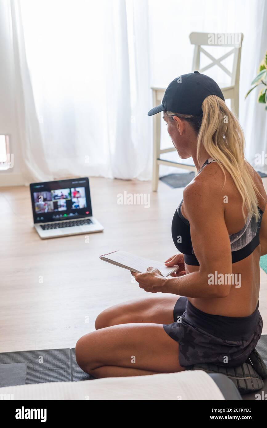 Depuis le dessus de Sportswoman en activité assis sur le sol avec un ordinateur portable et la liste de lecture des exercices pour l'entraînement Banque D'Images