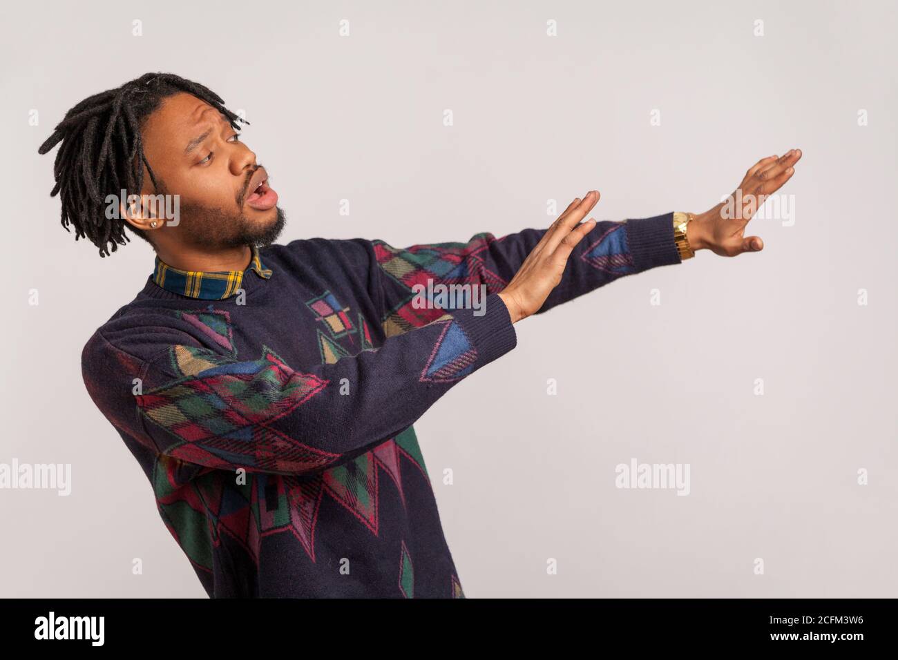Ne venez pas chez moi ! Portrait de profil de l'homme africain effrayé redressant ses bras, demandant de garder la distance, phobie. Prise de vue en studio isolée sur fond gris b Banque D'Images
