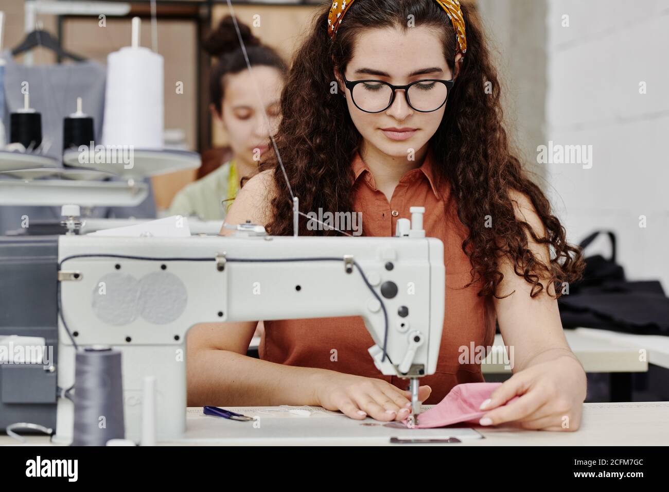 Couturière sérieuse assise par machine à coudre électrique tout en faisant l'épaule patins Banque D'Images