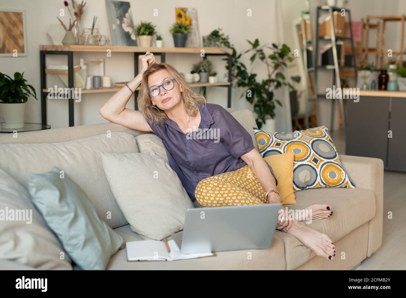 Femme d'affaires mûre blonde décontractée en tenue décontractée assise sur le canapé accueil Banque D'Images
