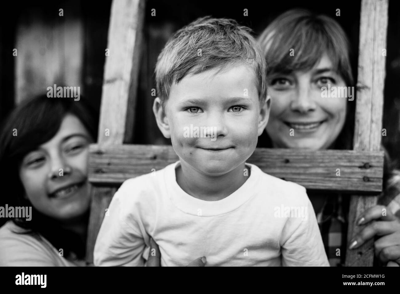 Portrait du petit garçon avec sa mère et sa sœur aînée. Photo en noir et blanc. Banque D'Images