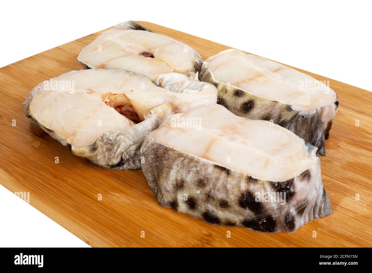Steaks de poisson-chat crus sur une planche à découper en bois isolés en studio sur fond blanc Banque D'Images