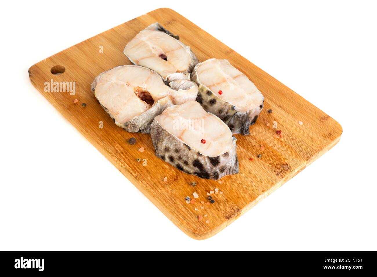 Steaks de poisson-chat crus sur une planche à découper en bois isolés en studio sur fond blanc Banque D'Images