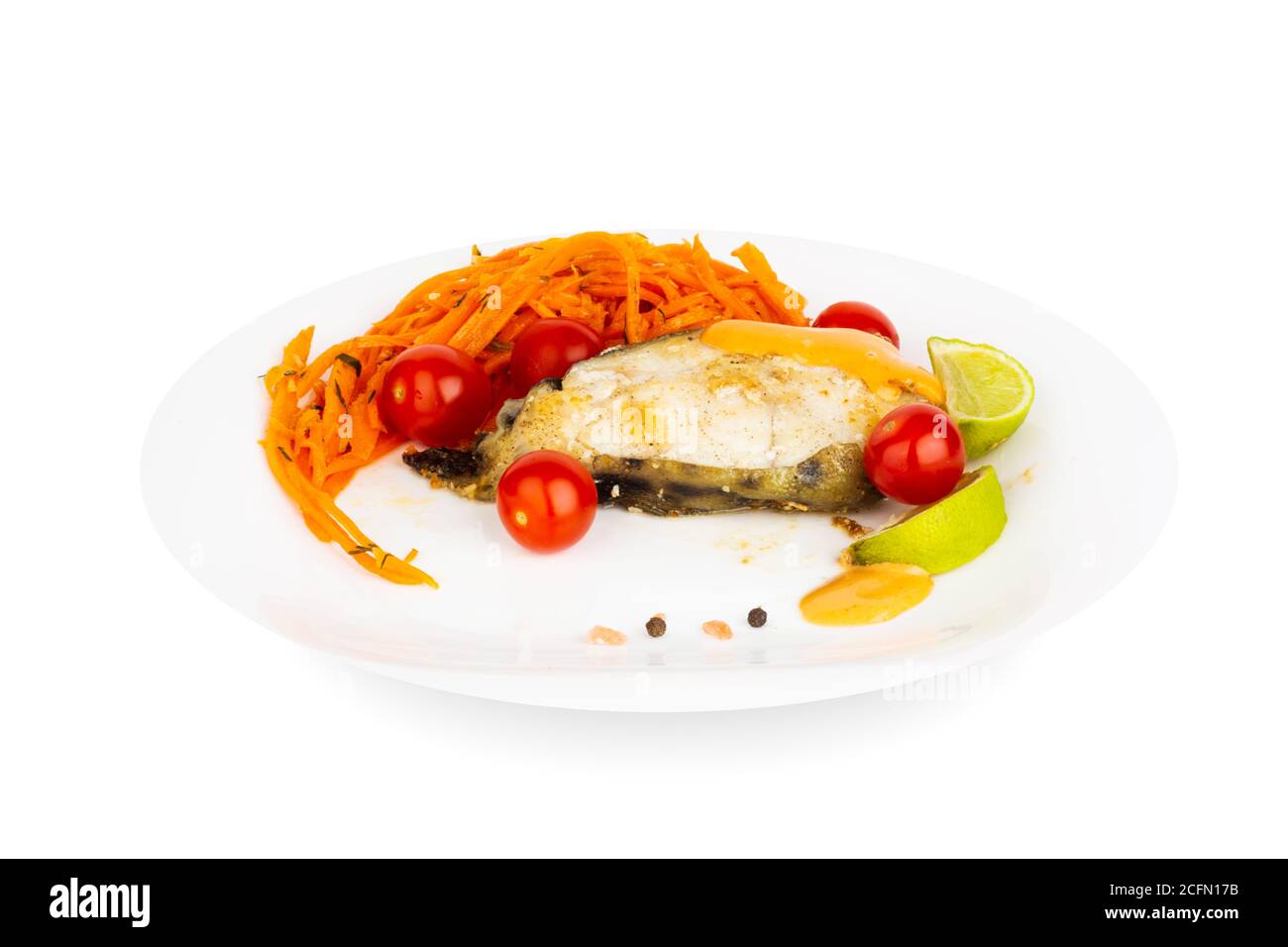 Steak de poisson-chat cuit frit avec garniture de sauce et de légumes sur plaque blanche isolée sur fond blanc Banque D'Images