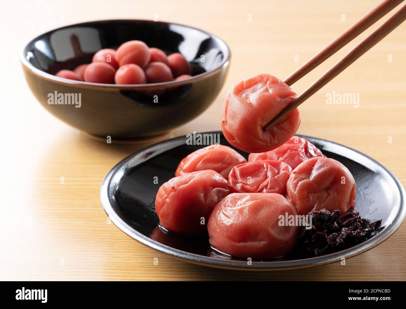 Prunes japonaises marinées sur fond de bois. Soulevez-le à l'aide de baguettes Banque D'Images