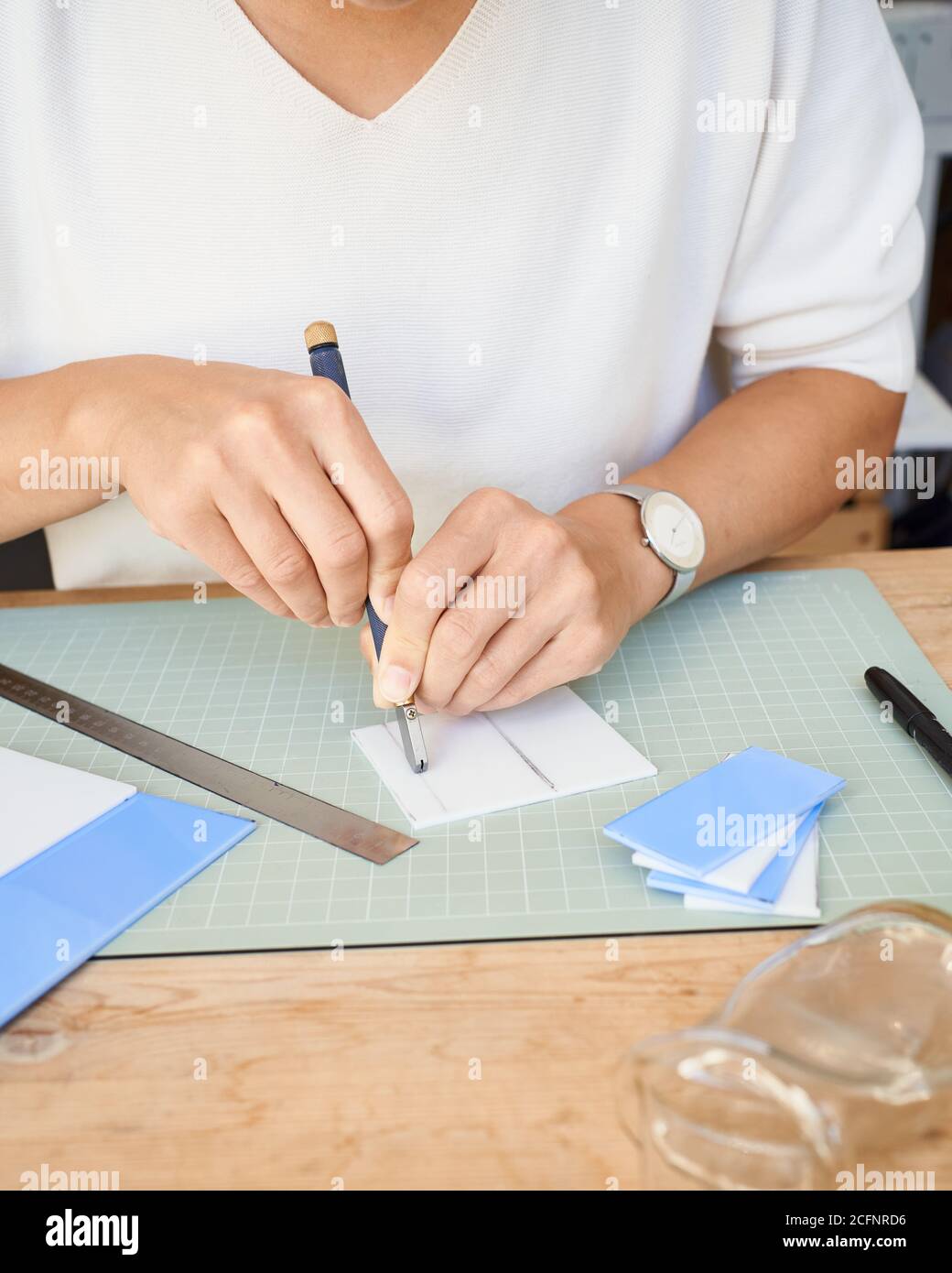 Femme entrepreneur sans visage coupant du verre dans une salle de travail artisanale. Femme d'affaires dessine la ligne sur l'assiette, ayant passe-temps, côté de l'agitation Banque D'Images