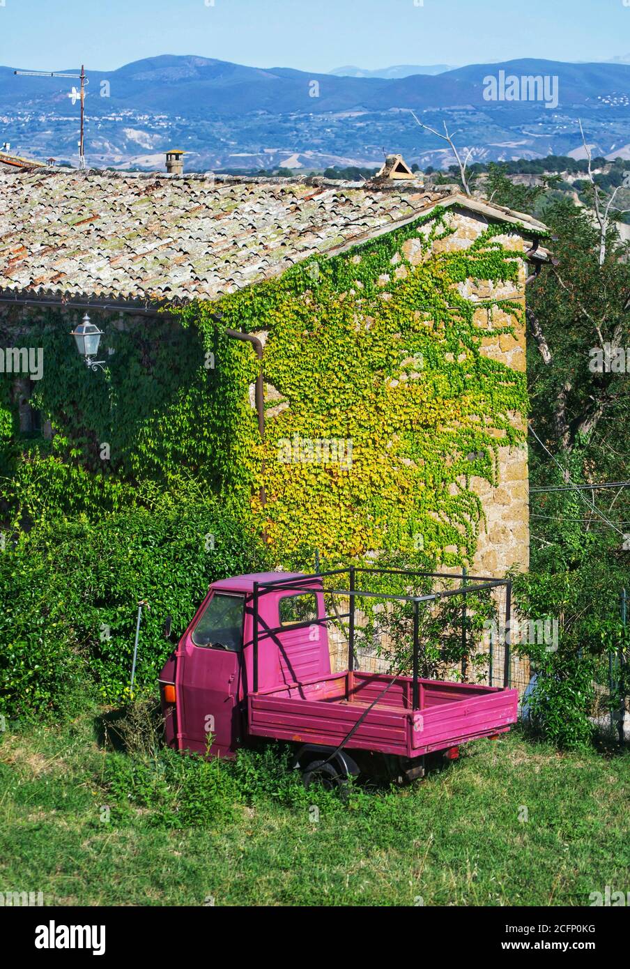 Ancienne maison à Civita di Bagnoregio avec trois roues roses dans le jardin Banque D'Images