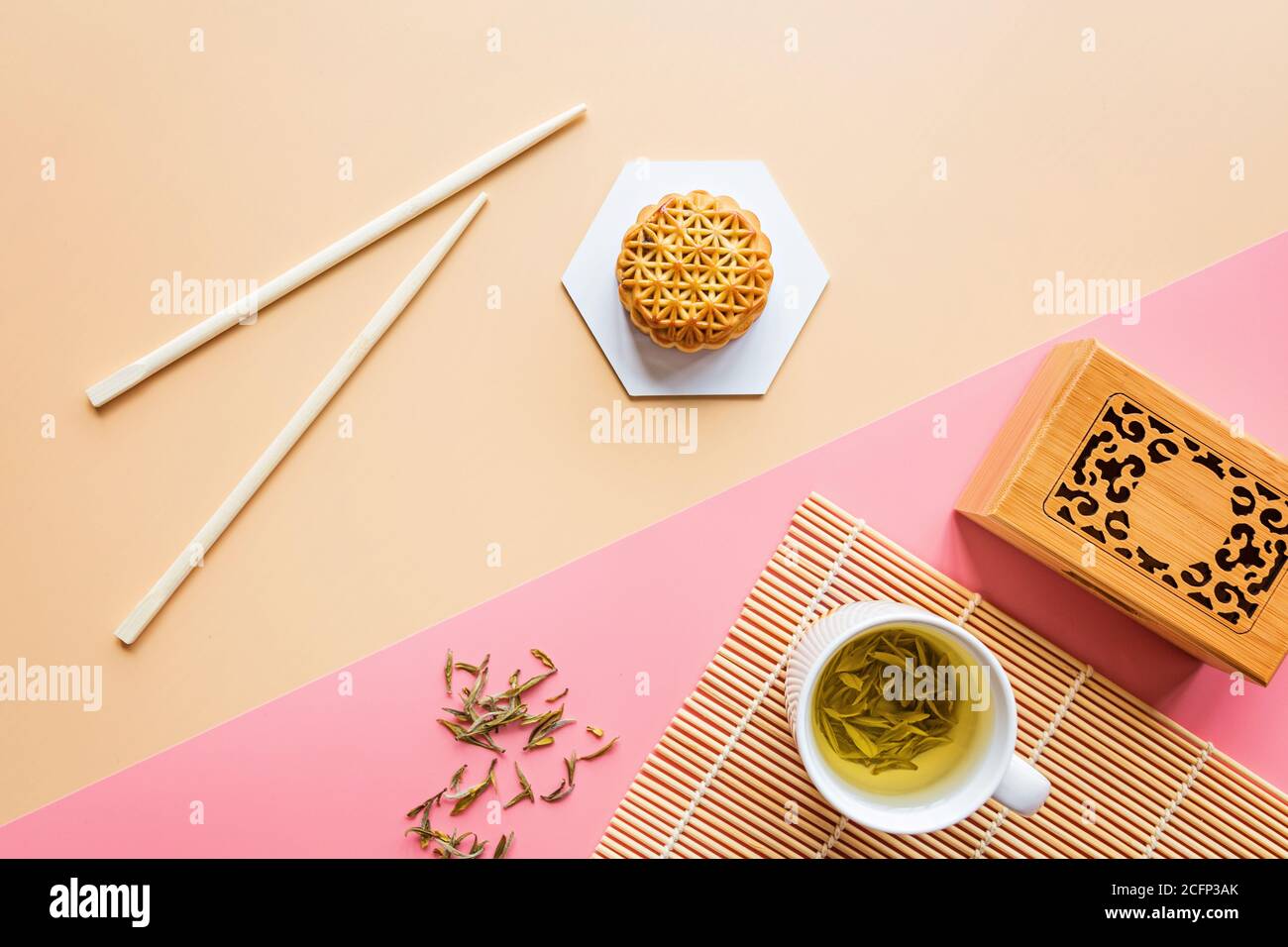 Mise à plat de dessert Festival chinois, Festival de mi-automne de gâteau de lune sur fond coloré avec du thé vert et de baguettes. Vue de dessus, copiez l'espace, immersive Banque D'Images