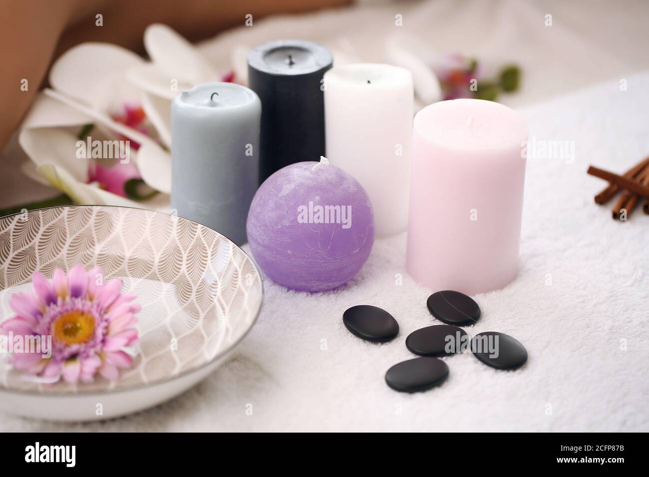 Articles de base pour les bougies et le spa sur une serviette dans la salle de bains, serviette, pierre de mer, orchidées blanches. Concept de kit de produits spa. Banque D'Images