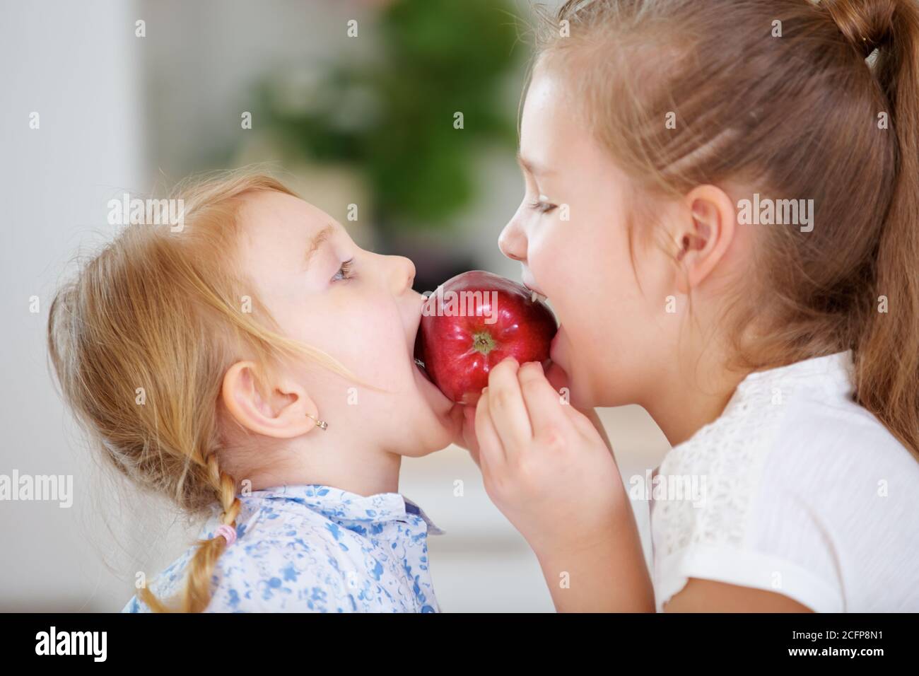 Deux enfants mangent une pomme rouge fraîche ensemble Banque D'Images