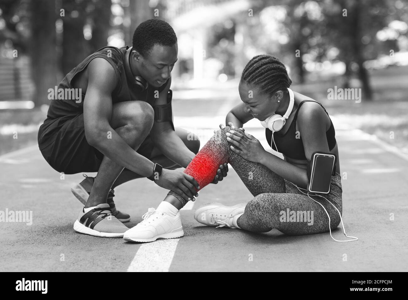 Traumatisme pendant la formation. Femme africaine ayant étendu la cheville après le jogging, BW Shot Banque D'Images