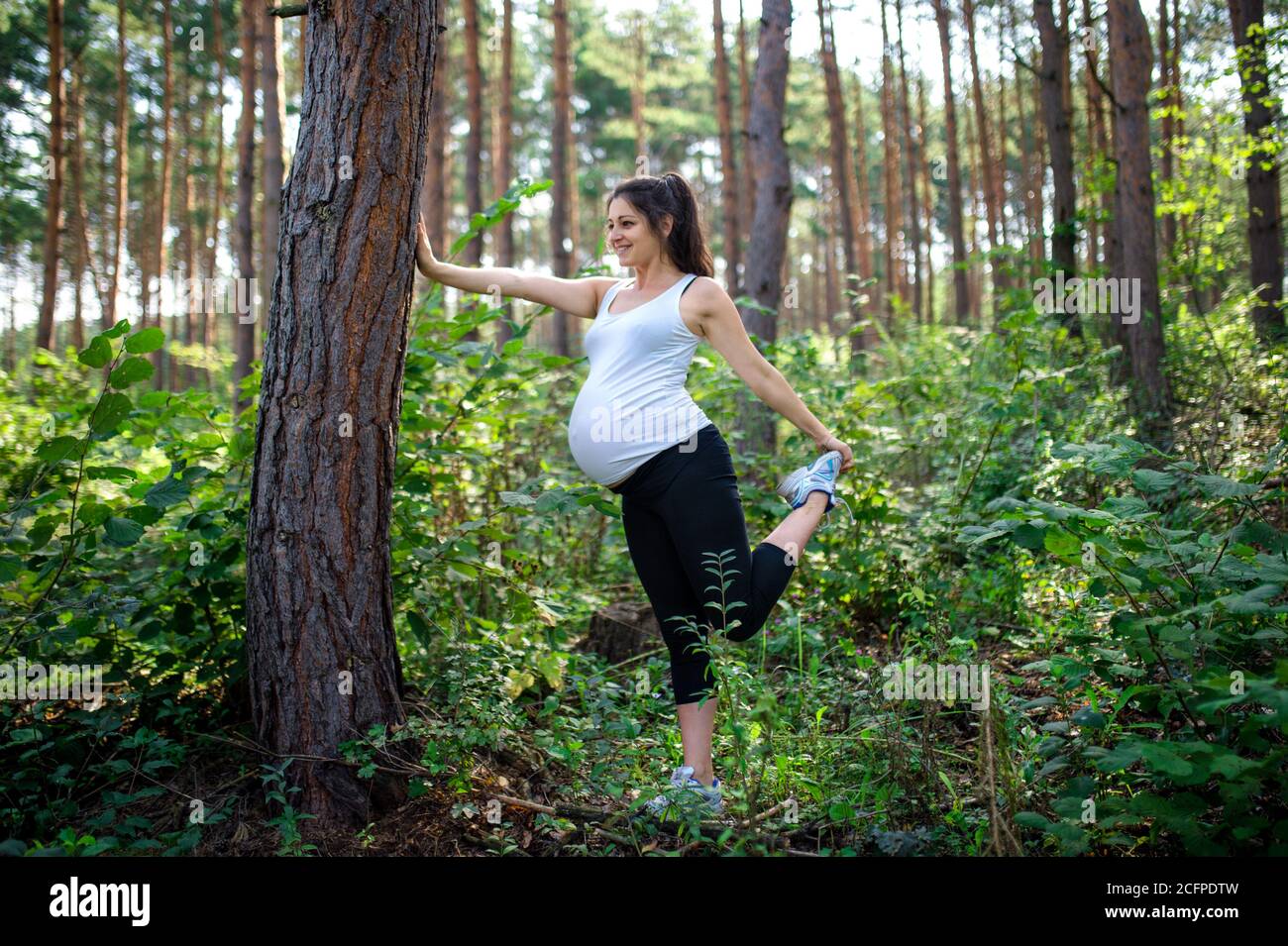 Portrait de la femme enceinte heureuse à l'extérieur dans la nature, faisant de l'exercice. Banque D'Images