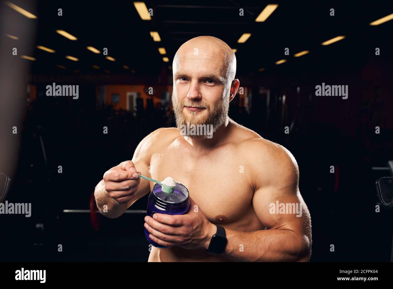 Un homme musclé qui hodging une cuillerée de poudre de protéine Banque D'Images