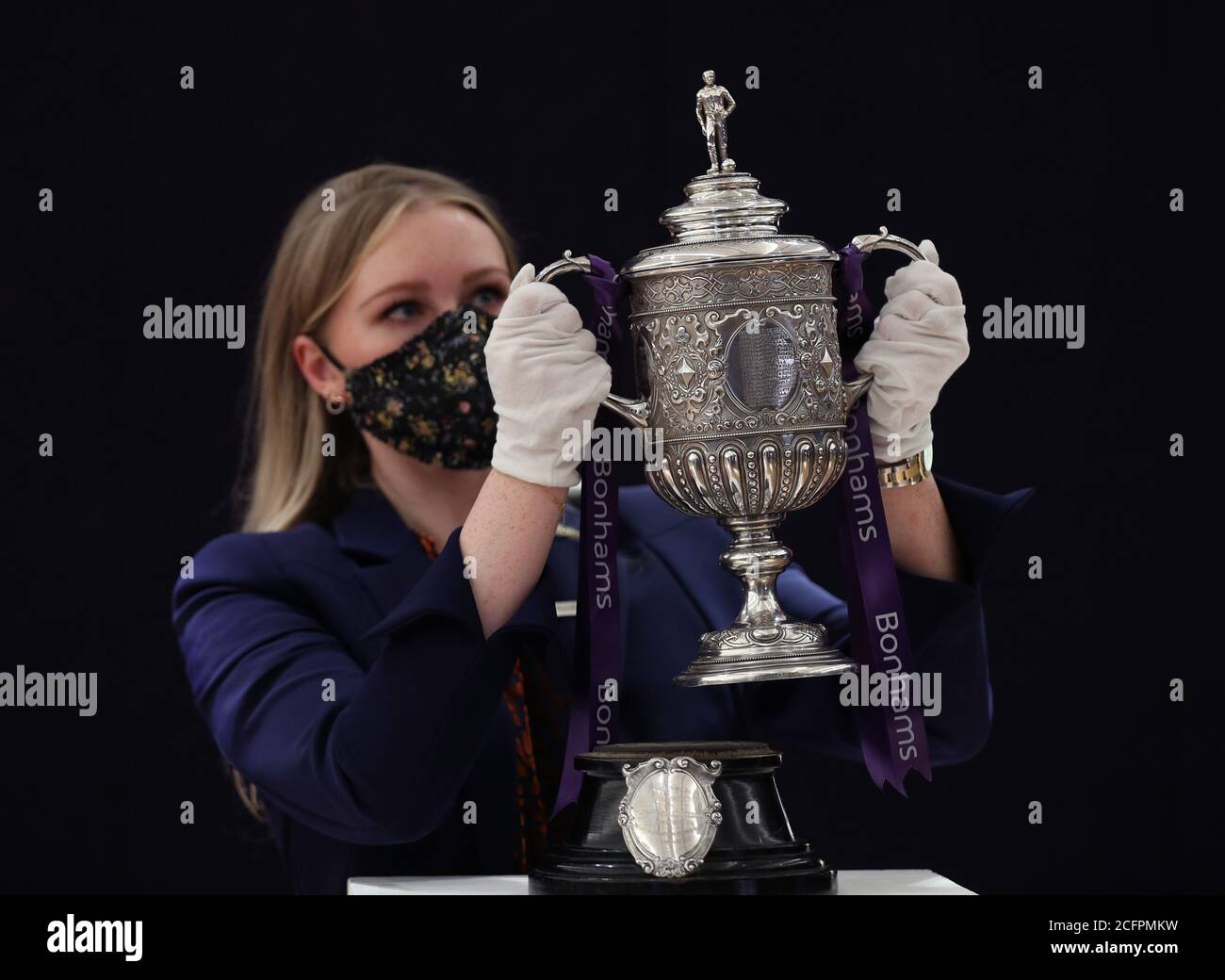 Laurel Kemp de Bonhams avec le plus ancien trophée de la coupe FA survivant lors d'un aperçu de la vente de trophées sportifs qui aura lieu sous le nom de saleroom de Bonhams New Bond Street le 29 septembre. La coupe argentée à deux manche, estimée entre 700,000 et 900,000 GBP, a été réalisée par Vaughton et fils de Birmingham en 1896 et a été présentée aux équipes gagnantes de la coupe FA entre 1896 et 1910, dont Manchester United, Manchester City, Everton, Newcastle United et Tottenham Hotspur. Banque D'Images