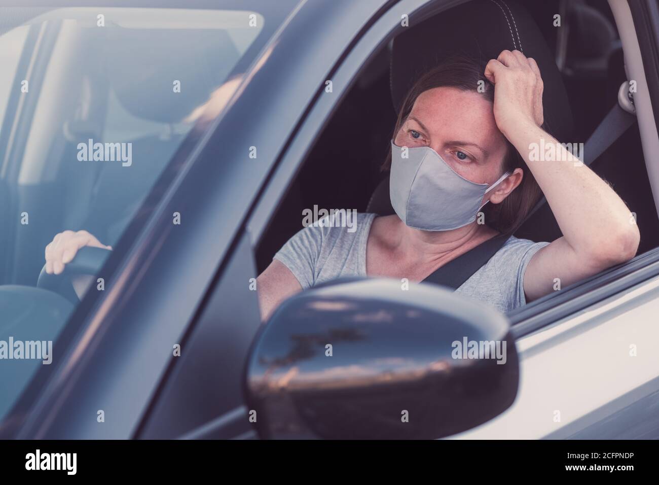 Femme ennuyée avec masque de protection dans la voiture dans un nouveau concept normal Banque D'Images