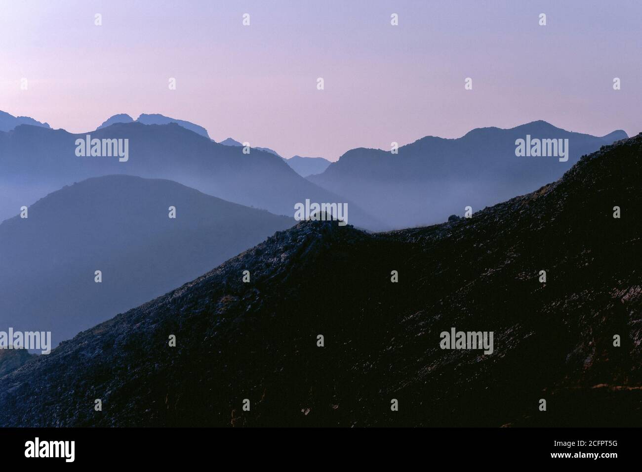 Le coucher du soleil approche le paysage accidenté au-delà de Lago Rosamarina en Sicile, en Italie, avec une brume rose douce. Banque D'Images