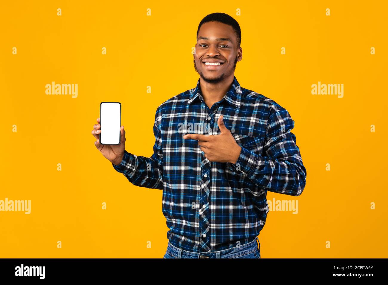 Joyeux Africain montrant smartphone écran vide, fond jaune, maquette Banque D'Images