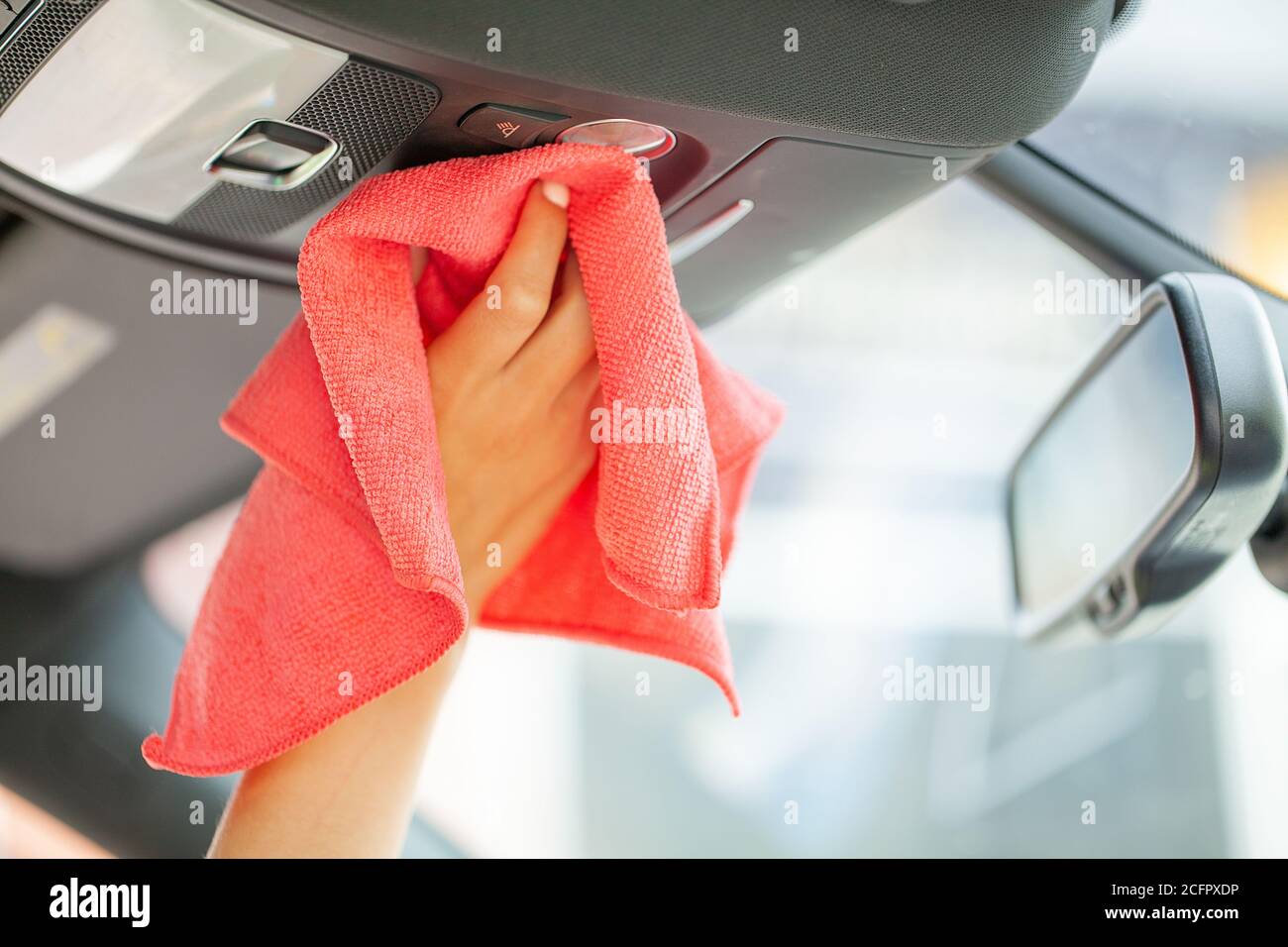 Gros plan d'une femme essuyant l'intérieur de la voiture avec un chiffon rouge Banque D'Images