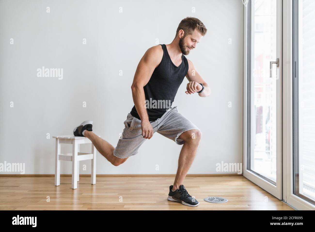 Beau jeune homme qui fait de l'activité à la maison avec un intelligent regardez Banque D'Images