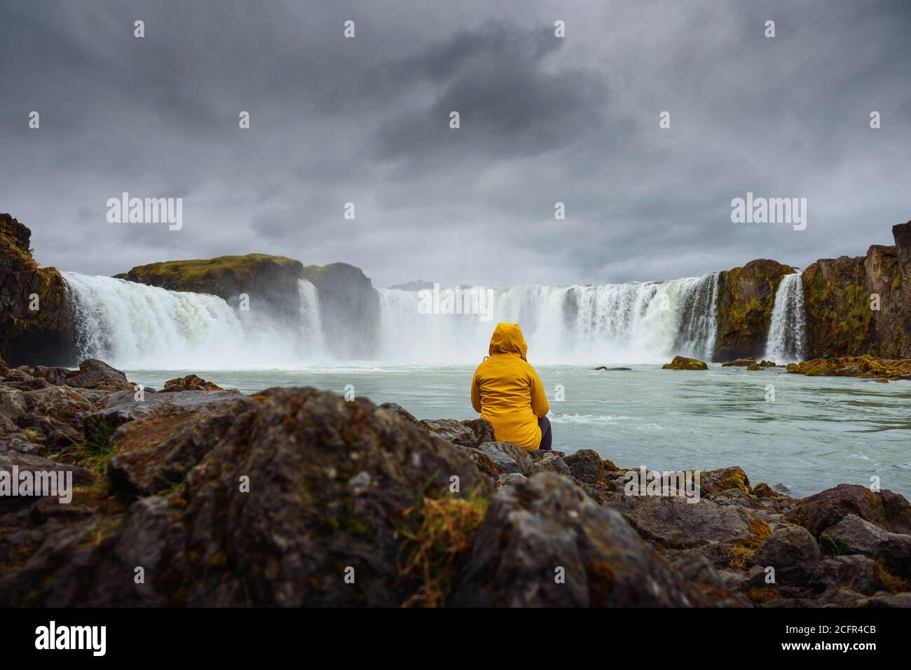 Tourisme dans une veste jaune se relaxant à la cascade Godafoss en Islande Banque D'Images