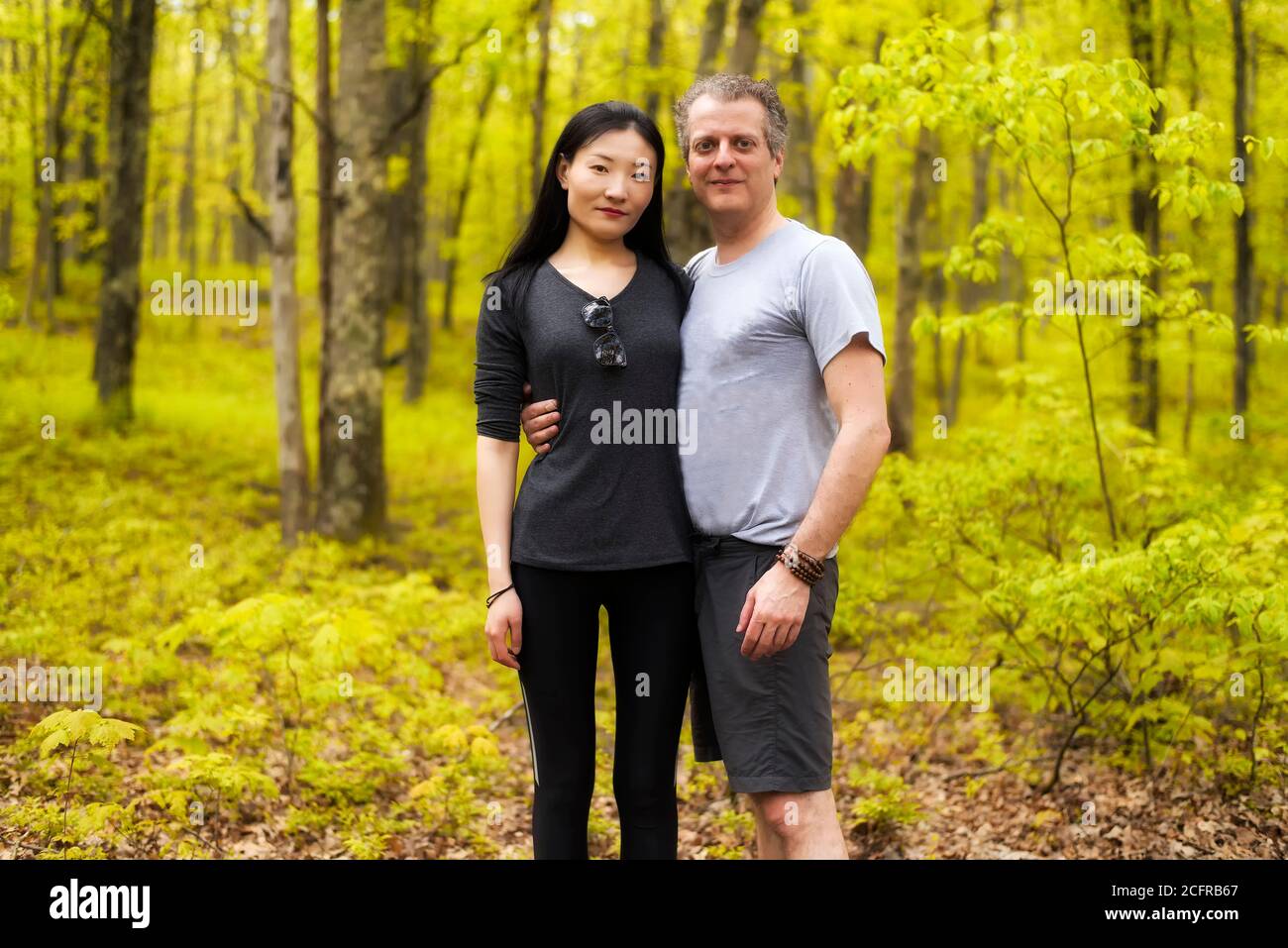 Un couple racial mixte qui fait de la randonnée dans une forêt à Bushkill Falls, en Pennsylvanie, le jour du printemps. Banque D'Images