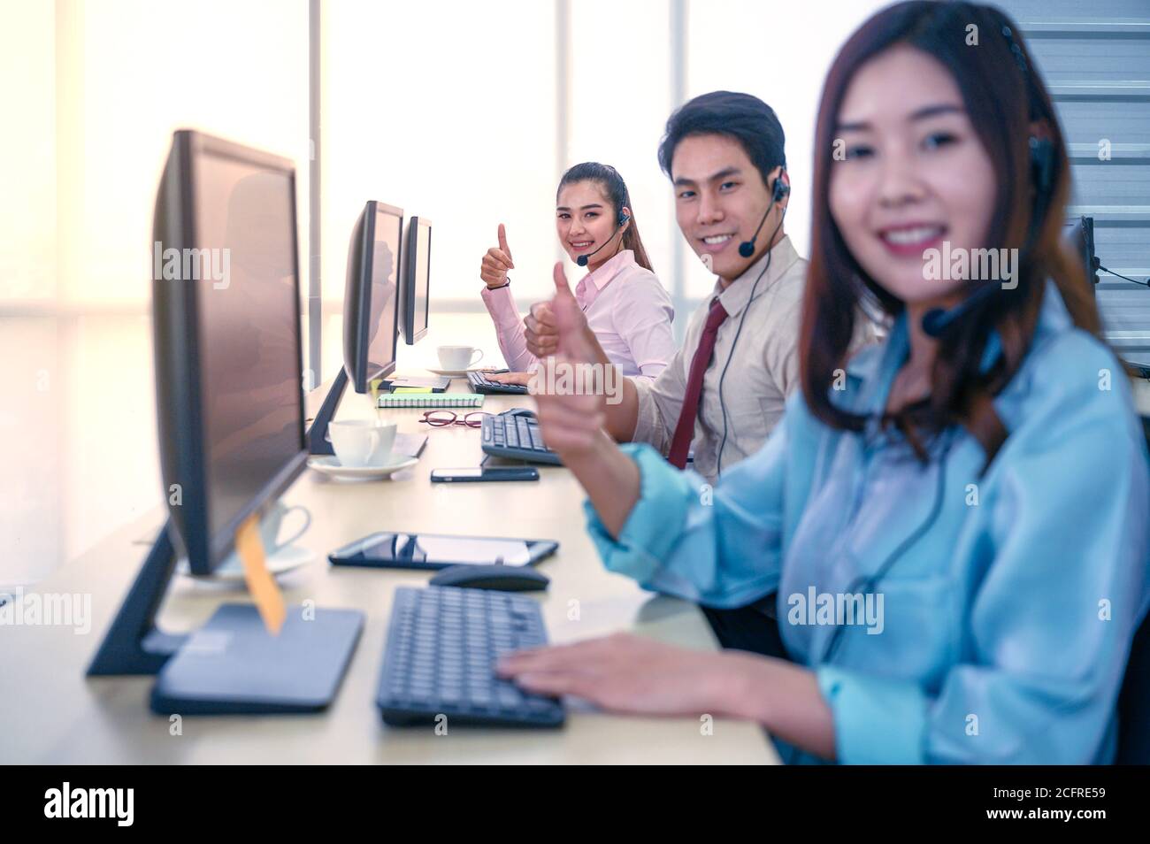 Un groupe de jeunes hommes d'affaires en équipe se mêle avec un micro-casque et un ordinateur au bureau. Concept d'assistance aux entreprises. Banque D'Images