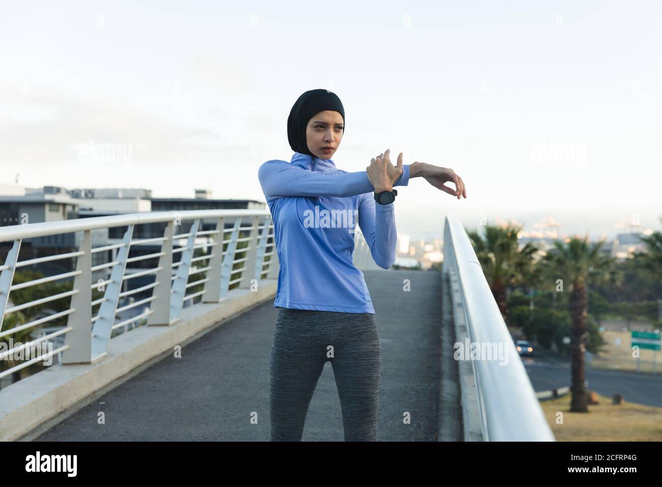 Femme en hijab effectuant un exercice d'étirement sur une passerelle Banque D'Images Femme en hijab effectuant un exercice d'étirement sur une passerelle Banque D'Images