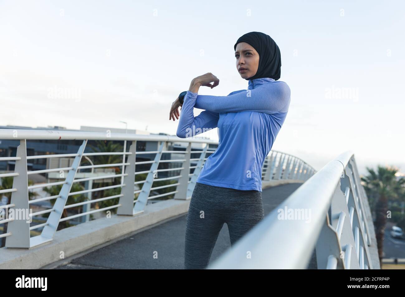 Femme en hijab effectuant un exercice d'étirement sur une passerelle Banque D'Images Femme en hijab effectuant un exercice d'étirement sur une passerelle Banque D'Images