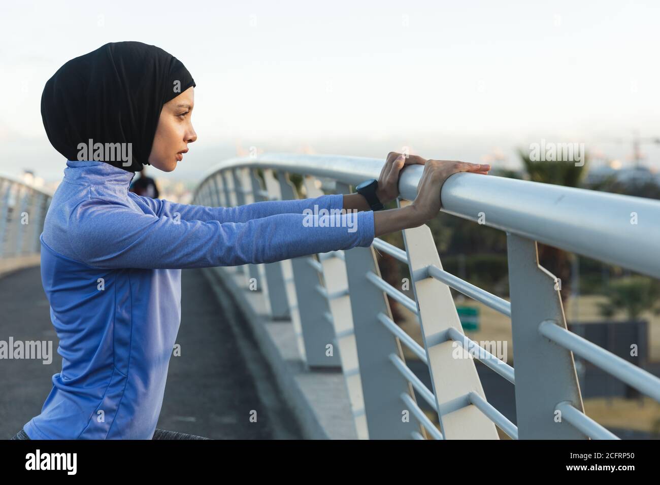 Femme en hijab effectuant un exercice d'étirement sur une passerelle Banque D'Images Femme en hijab effectuant un exercice d'étirement sur une passerelle Banque D'Images