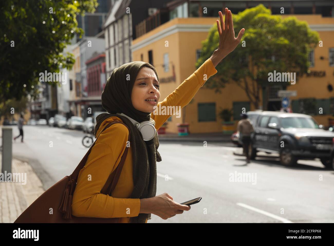 Une femme en hijab hante un taxi dans la rue Banque D'Images Une femme en hijab hante un taxi dans la rue Banque D'Images