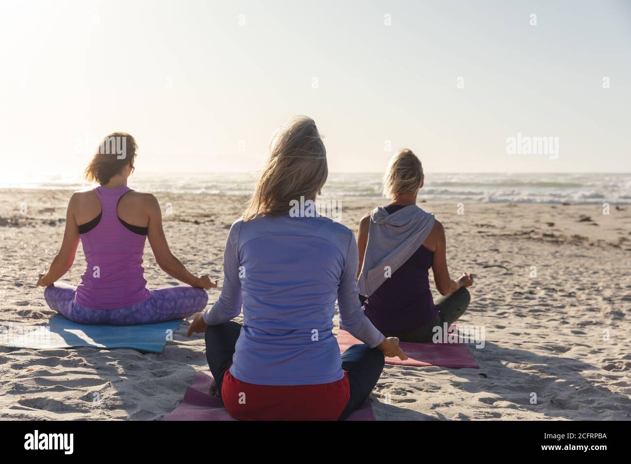 Vue arrière du groupe de femmes pratiquant le yoga sur le plage Banque D'Images Vue arrière du groupe de femmes pratiquant le yoga sur le plage Banque D'Images