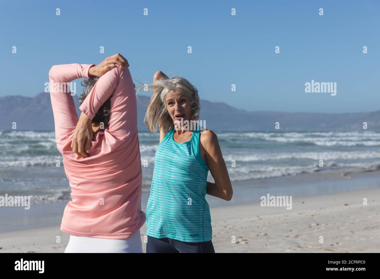 Deux femmes effectuant des exercices d'étirement à la plage Banque D'Images Deux femmes effectuant des exercices d'étirement à la plage Banque D'Images