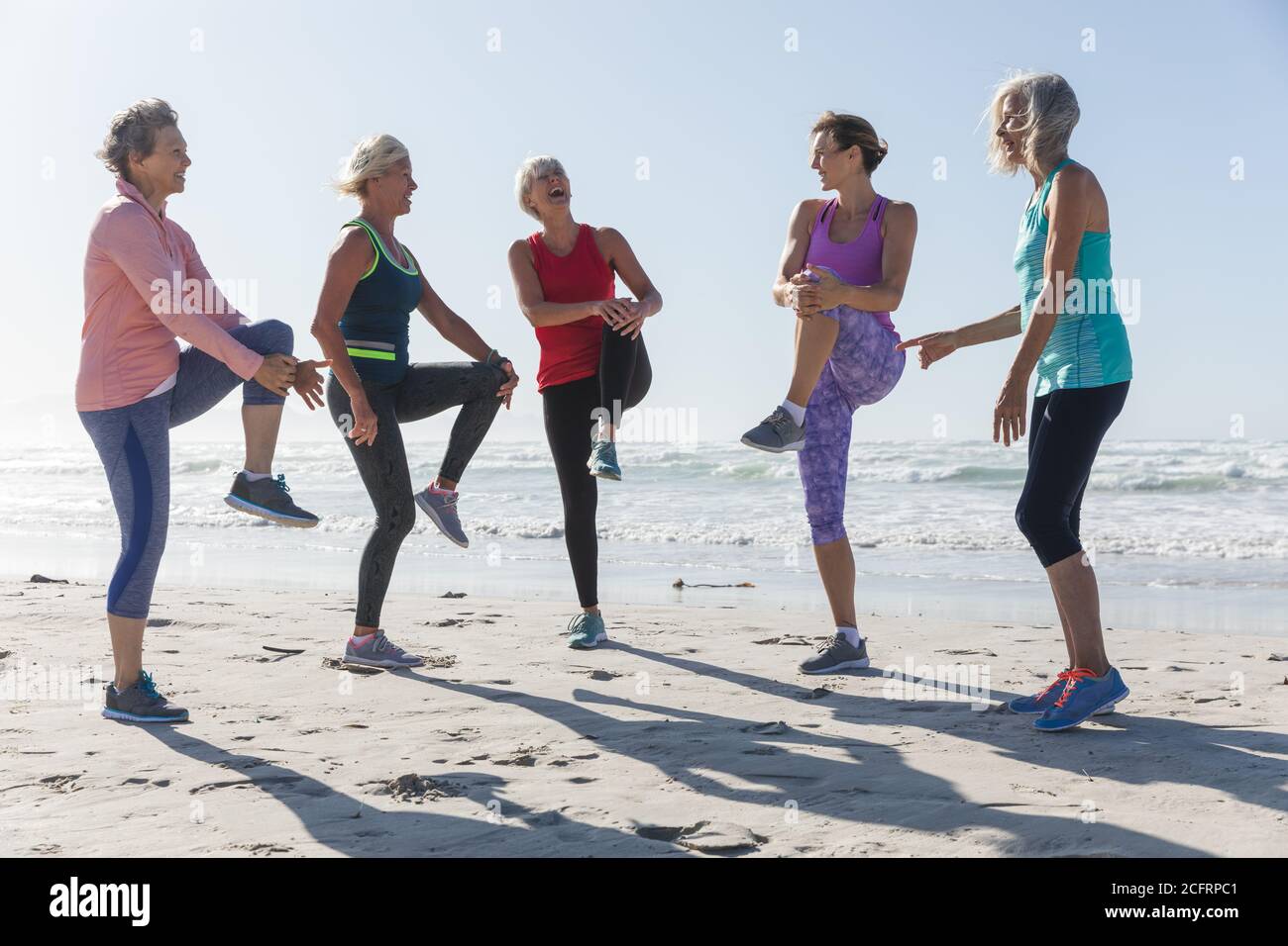 Groupe de femmes effectuant des exercices d'étirement à la plage Banque D'Images Groupe de femmes effectuant des exercices d'étirement à la plage Banque D'Images