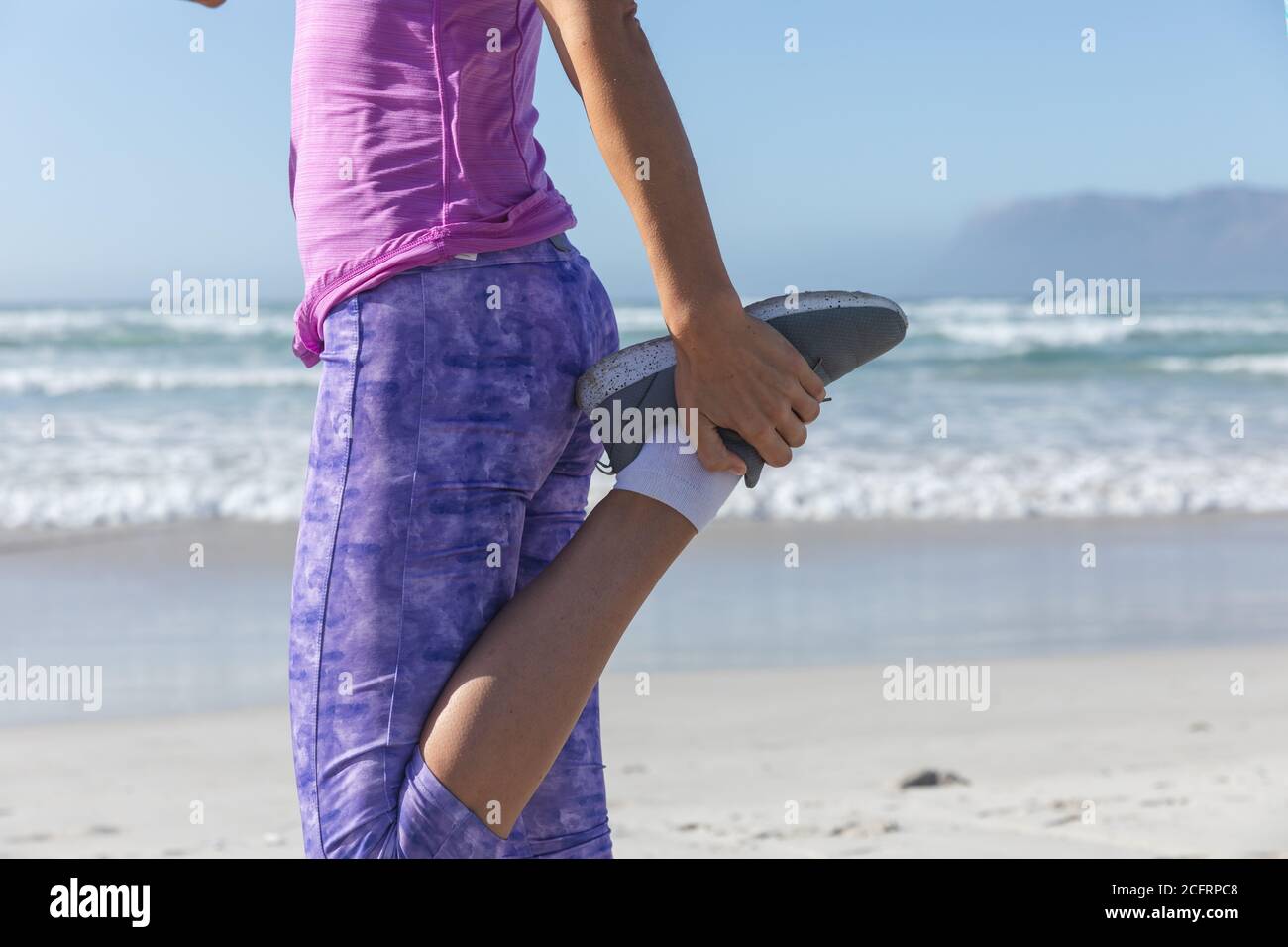 Section basse de la femme effectuant des exercices d'étirement à la plage Banque D'Images Section basse de la femme effectuant des exercices d'étirement à la plage Banque D'Images