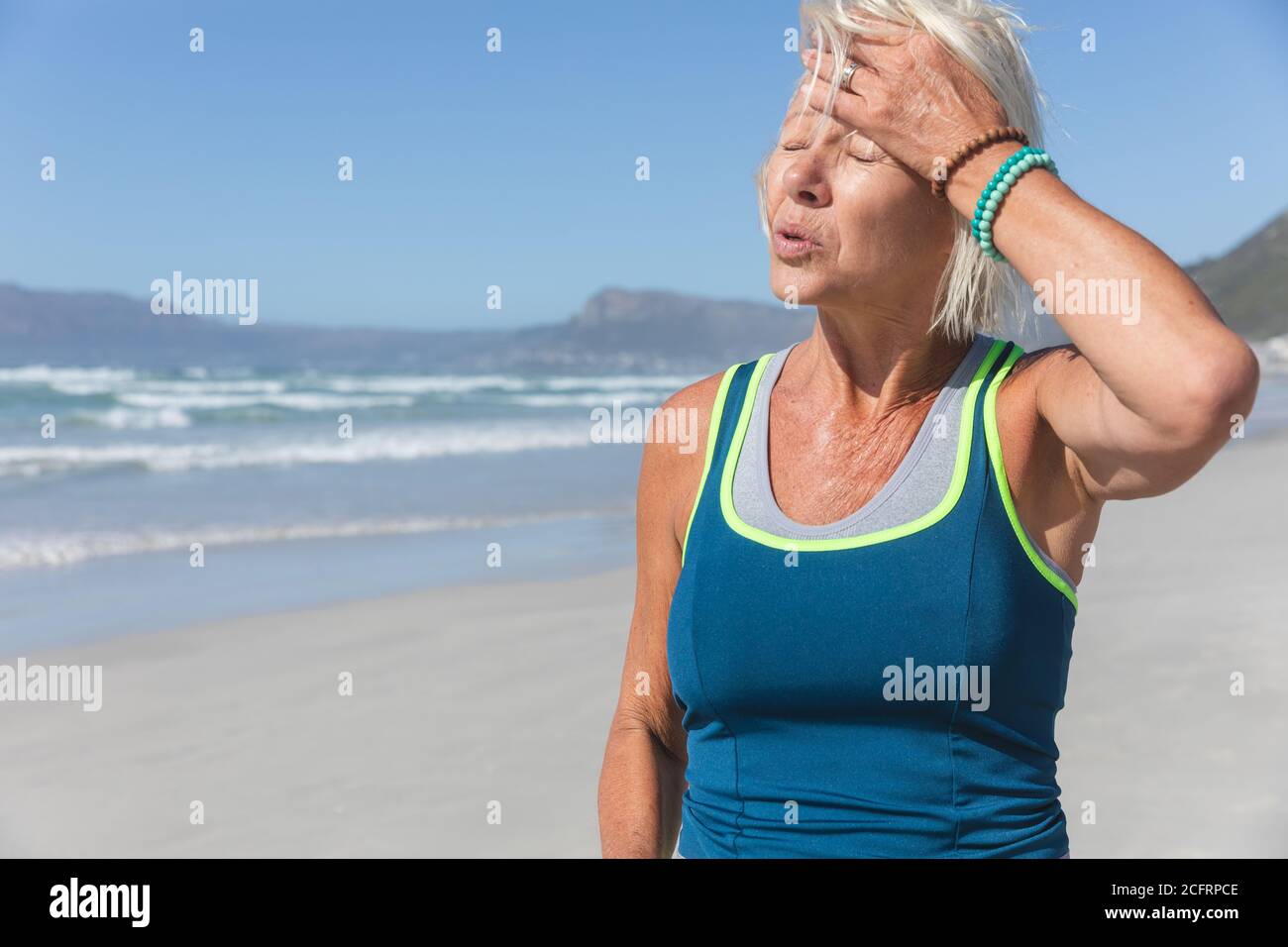 Femme âgée en train de faire une pause en courant sur la plage Banque D'Images Femme âgée en train de faire une pause en courant sur la plage Banque D'Images