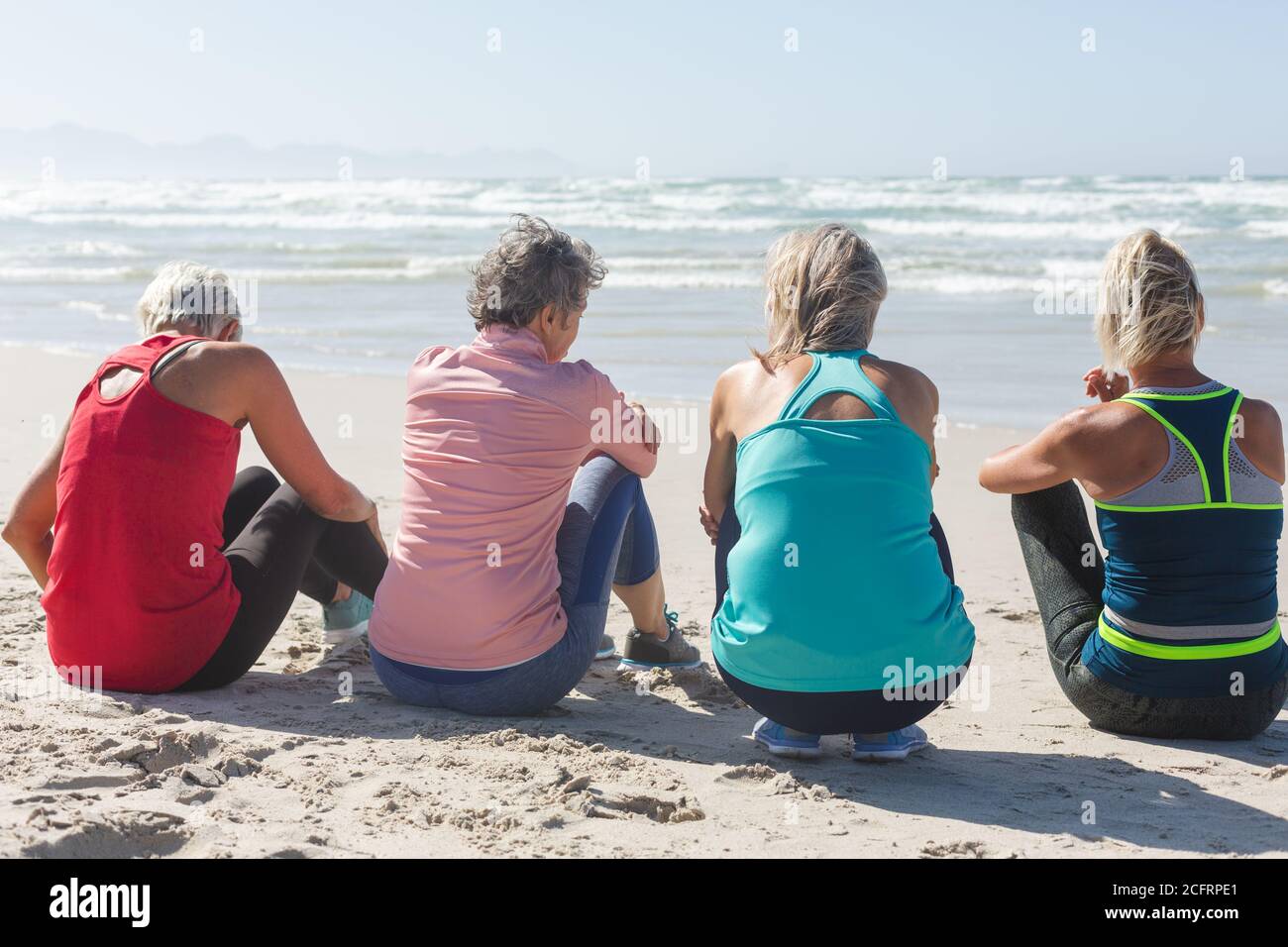 Vue arrière du groupe de femmes assis sur la plage Banque D'Images Vue arrière du groupe de femmes assis sur la plage Banque D'Images