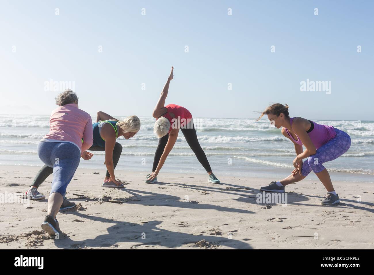 Groupe de femmes effectuant des exercices d'étirement à la plage Banque D'Images Groupe de femmes effectuant des exercices d'étirement à la plage Banque D'Images
