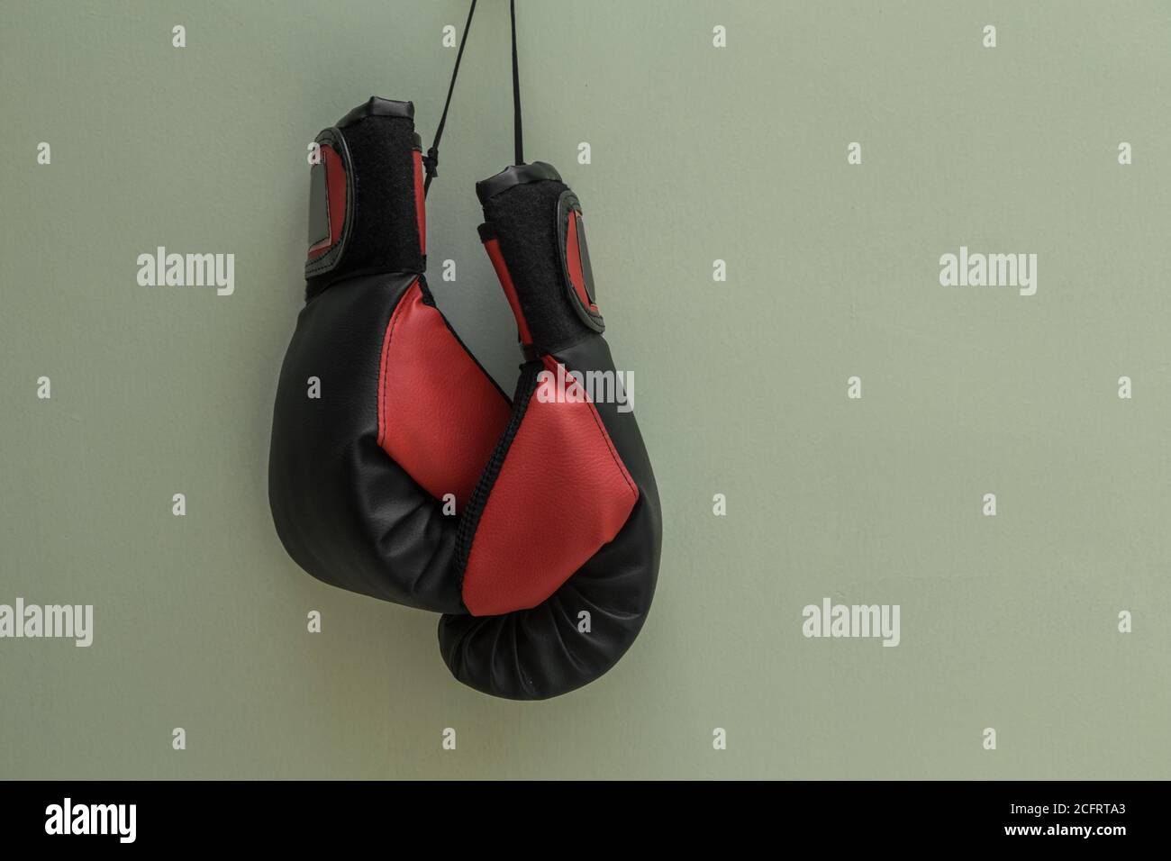 gants de boxe rouge et noir suspendus de près avec un fond blanc, studio Banque D'Images